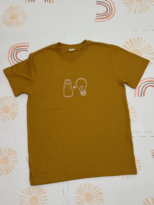 Salt & Light Tees embroidered in cream thread as a line art of salt and light icons. Shirt color is in mustard.